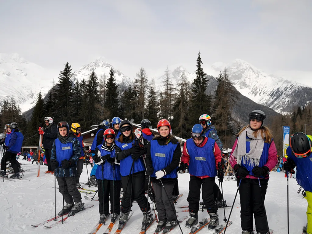 Gruppenfoto auf Skiern vor verschneiten Bergen.